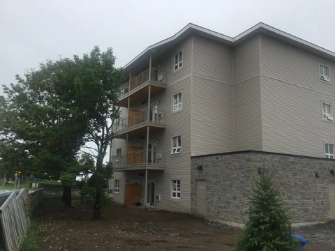 a large apartment building with a stone wall and a tree